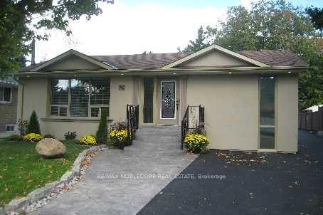Single-story beige house with a covered entry, stone walkway, and dark driveway.