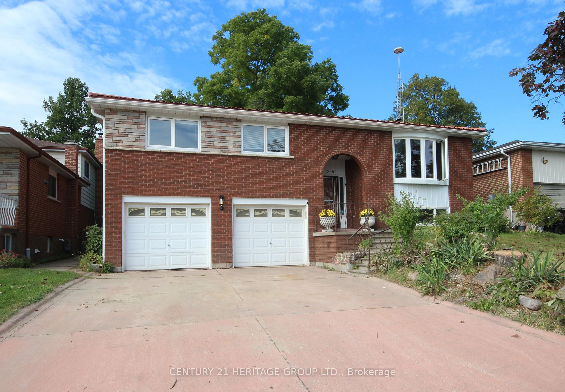 Two-storey red brick house with two white garage doors, an arched entry, and a wide concrete driveway.