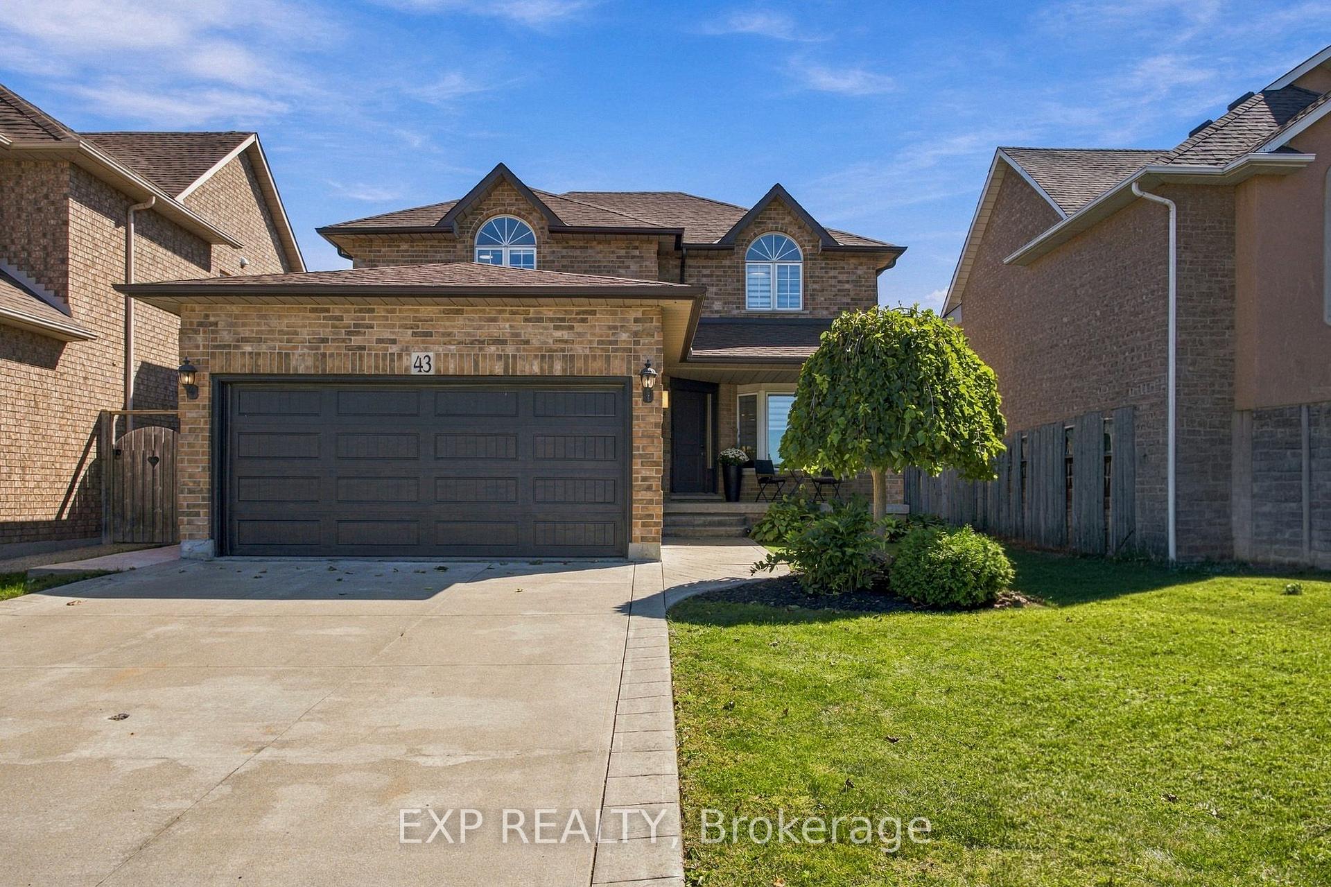 Brick two-storey home with a double garage, arched upper windows, and a landscaped lawn.