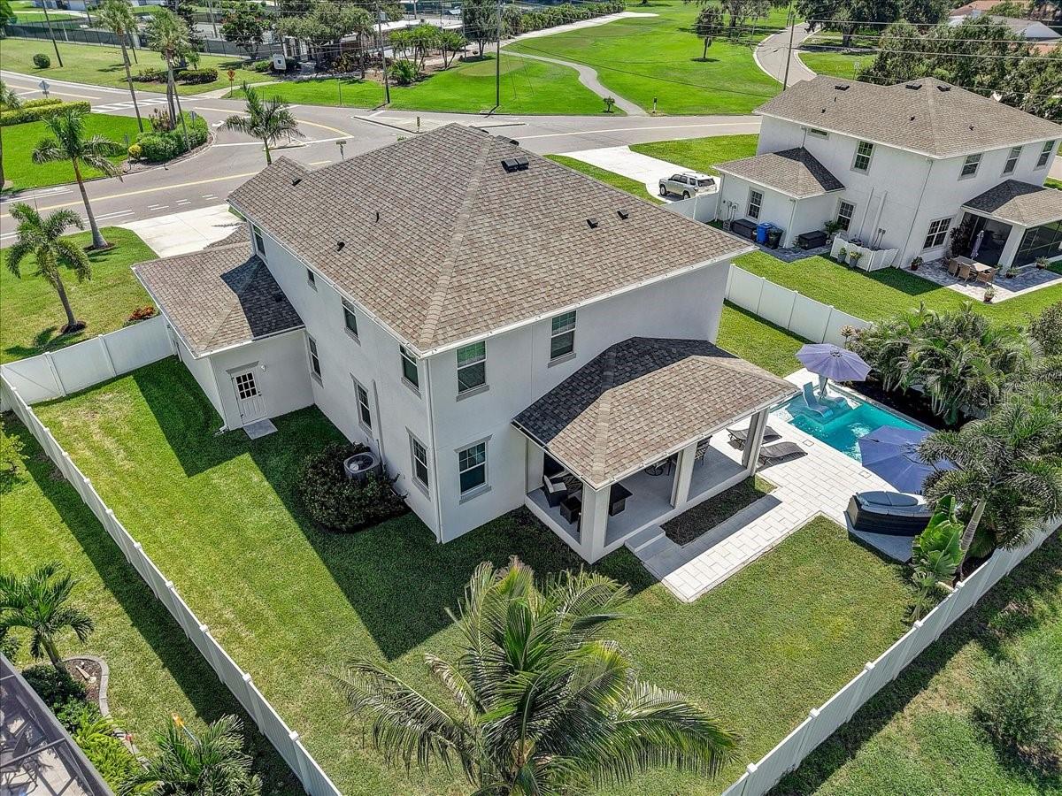 Aerial view of a two-story home with a fenced lawn, swimming pool, and covered patio.