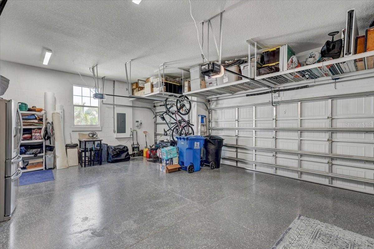 Garage with a speckled epoxy floor, overhead storage shelves, and bicycles.