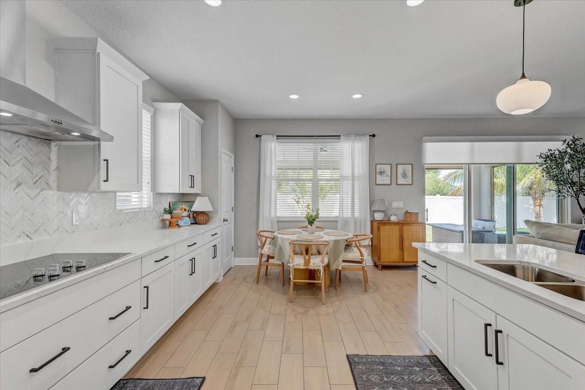 Bright white kitchen with a large island, dining table, and sliding glass doors to a patio.
