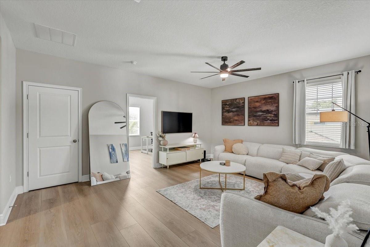 Staged living room with a white sectional, pale wood floors, and a large leaning mirror.