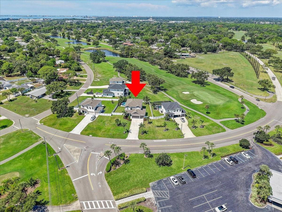 Aerial view of the home beside a golf course, marked with a red arrow.
