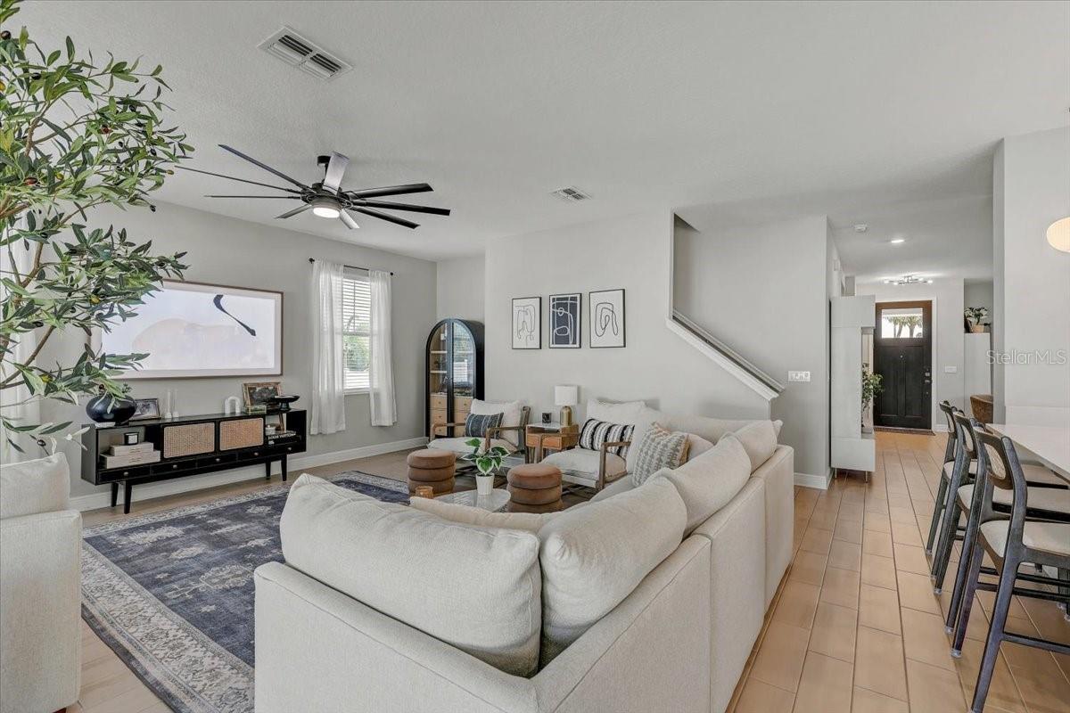 Open-plan living room with a white sectional, patterned rug, and black media console.