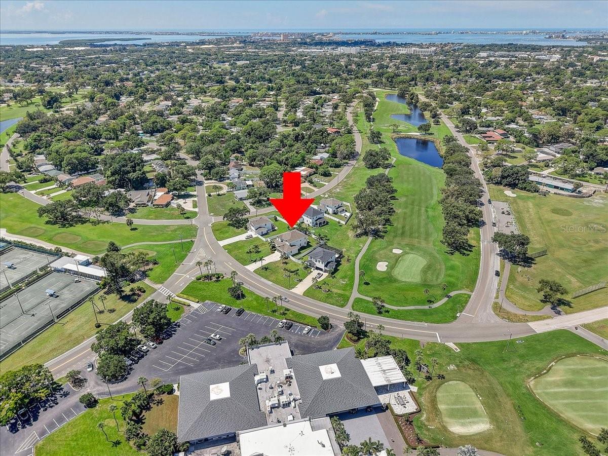Aerial view of the marked home beside a golf course, with ponds and distant water.