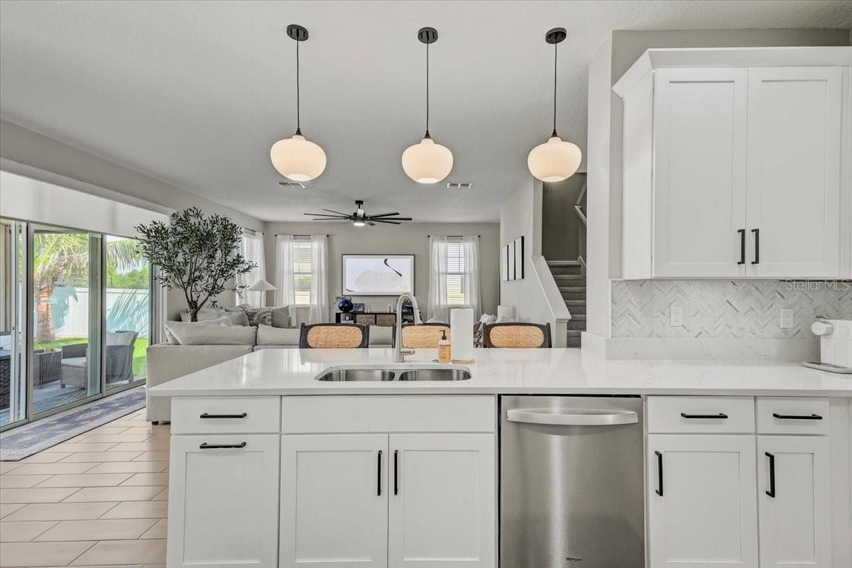 Open-plan kitchen with a large white island, pendant lights, and sliding glass doors to the patio.