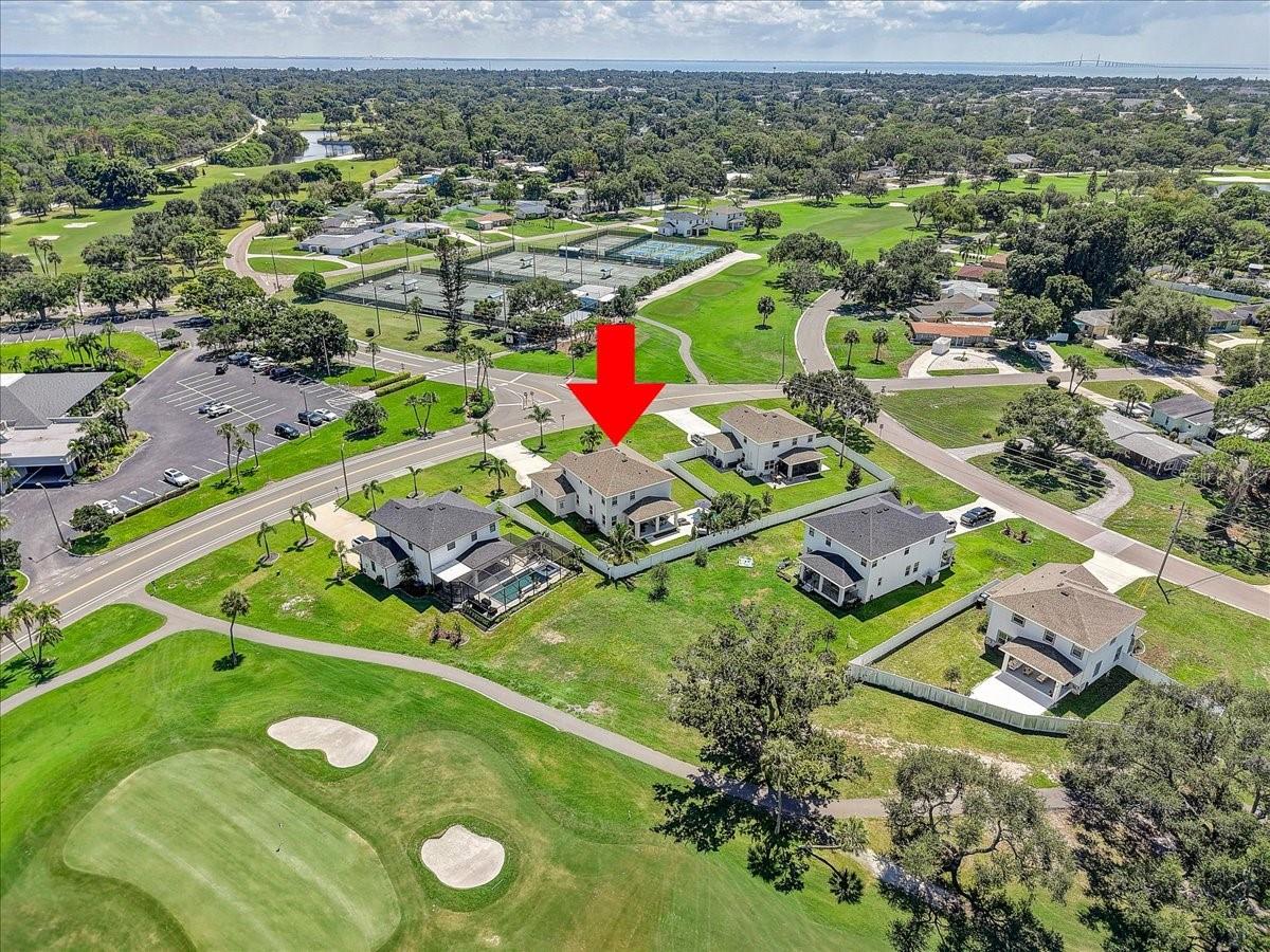 Aerial view of the home beside a golf course, marked by a red arrow.
