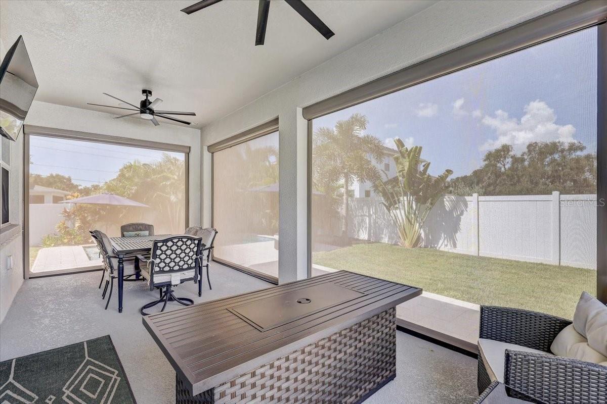 Screened patio with outdoor dining and lounge seating overlooking a fenced lawn.