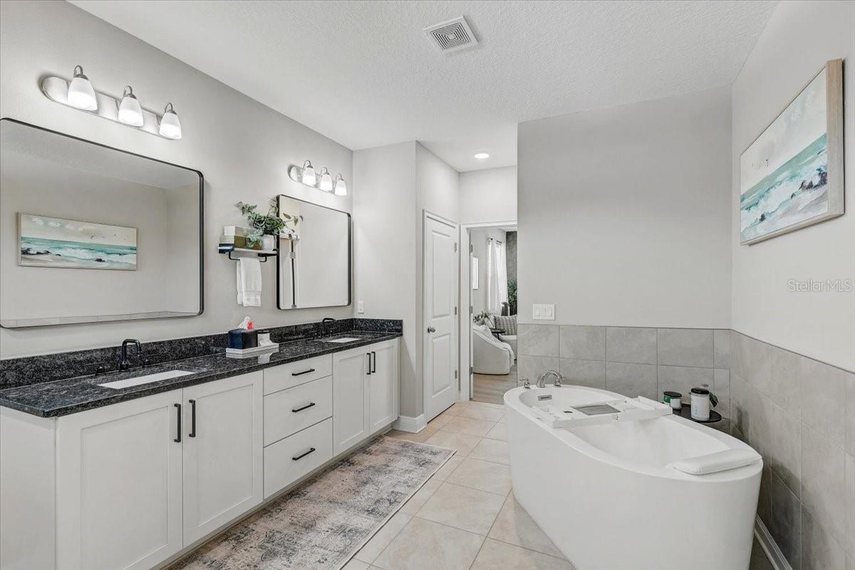 Bathroom with freestanding soaking tub and long double-mirror vanity.
