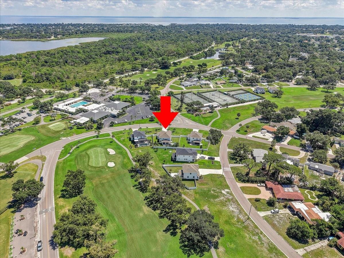 Aerial neighborhood view with a red arrow marking a home beside the golf course.