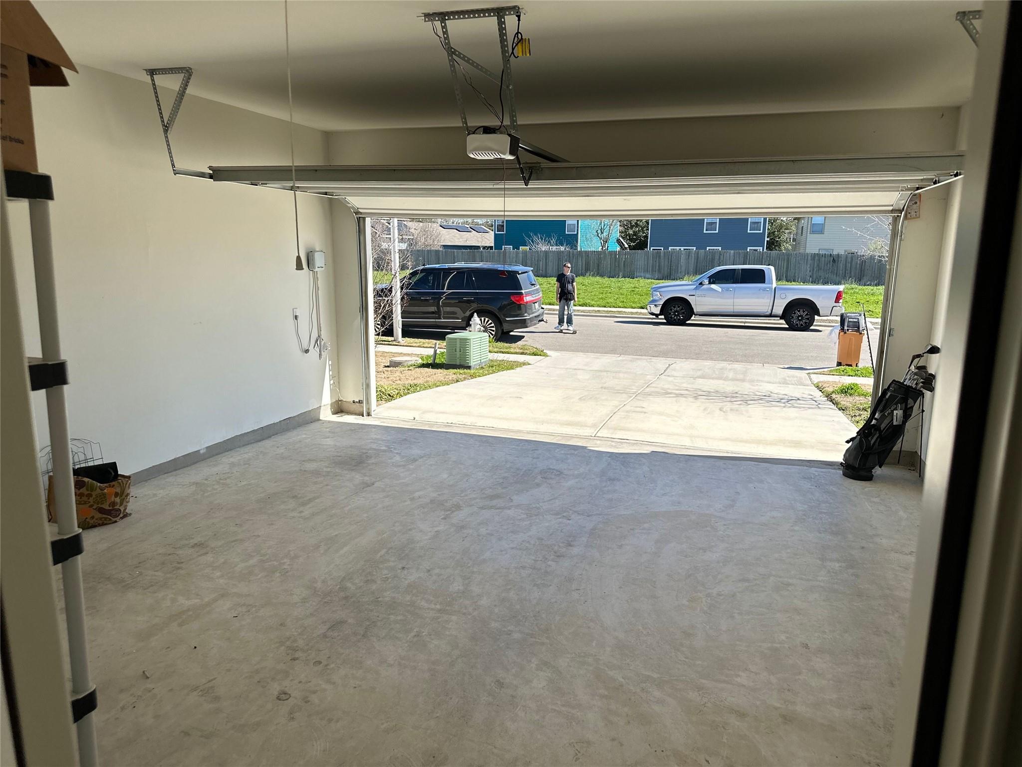 Empty garage with concrete floor and open overhead door facing the driveway.