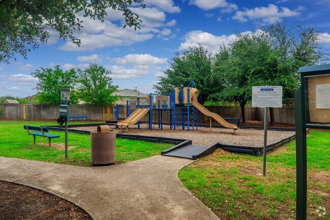 Neighborhood playground with blue and tan play equipment, two slides, benches, and a concrete path.