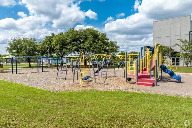Playground with colorful climbing frames and slides beside a grassy lawn.