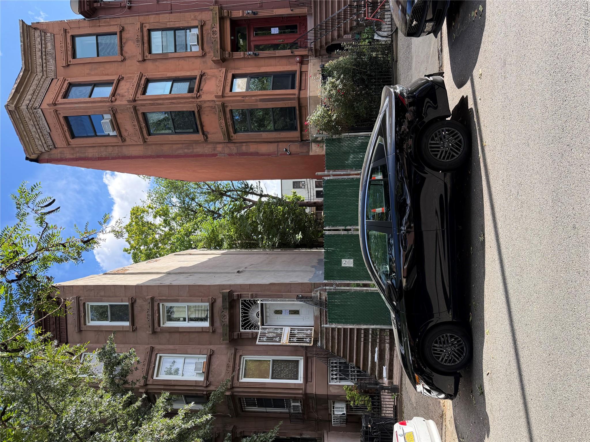 900A Greene Avenue brownstone beside a fenced lot, with ornate facades, bay windows, and front stoops.