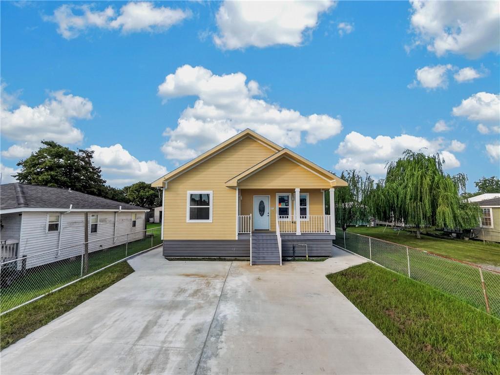 Yellow single-story home with a covered porch and wide concrete driveway.