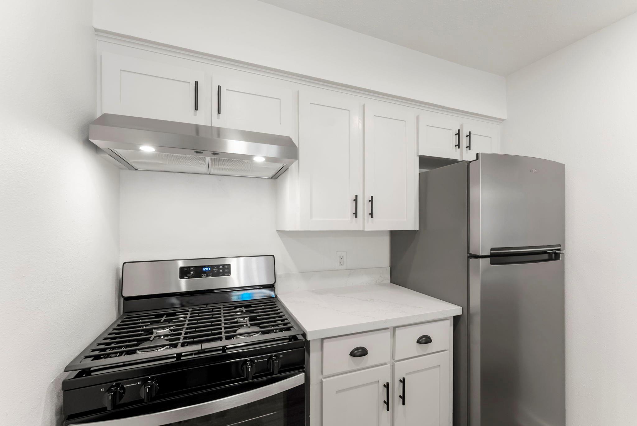 Kitchen with white shaker cabinets, a black gas range, and stainless steel appliances.