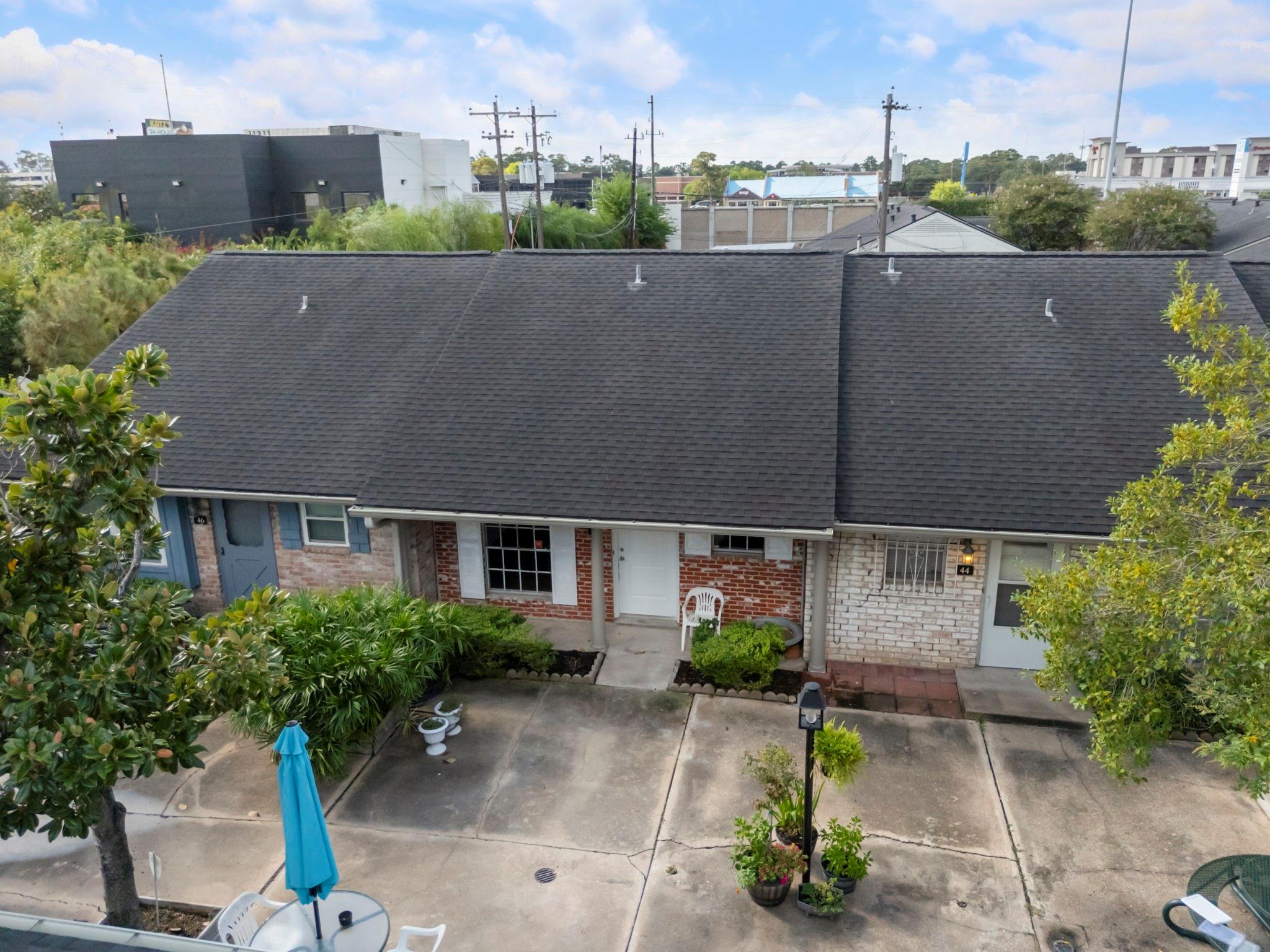 Attached brick townhomes with dark roofs overlook a shared courtyard with patio furniture and landscaped entries.