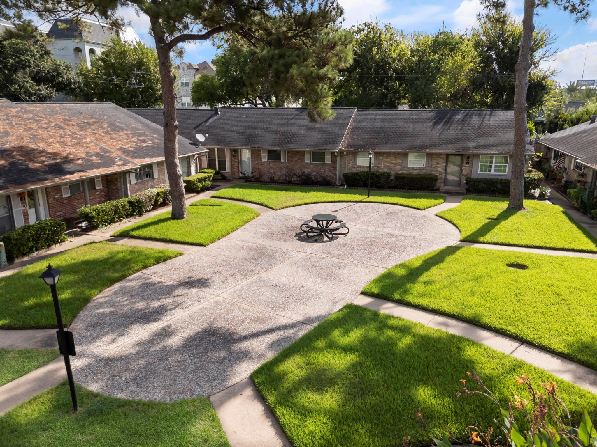 Brick homes surround a landscaped courtyard with curving walkways and a picnic table.
