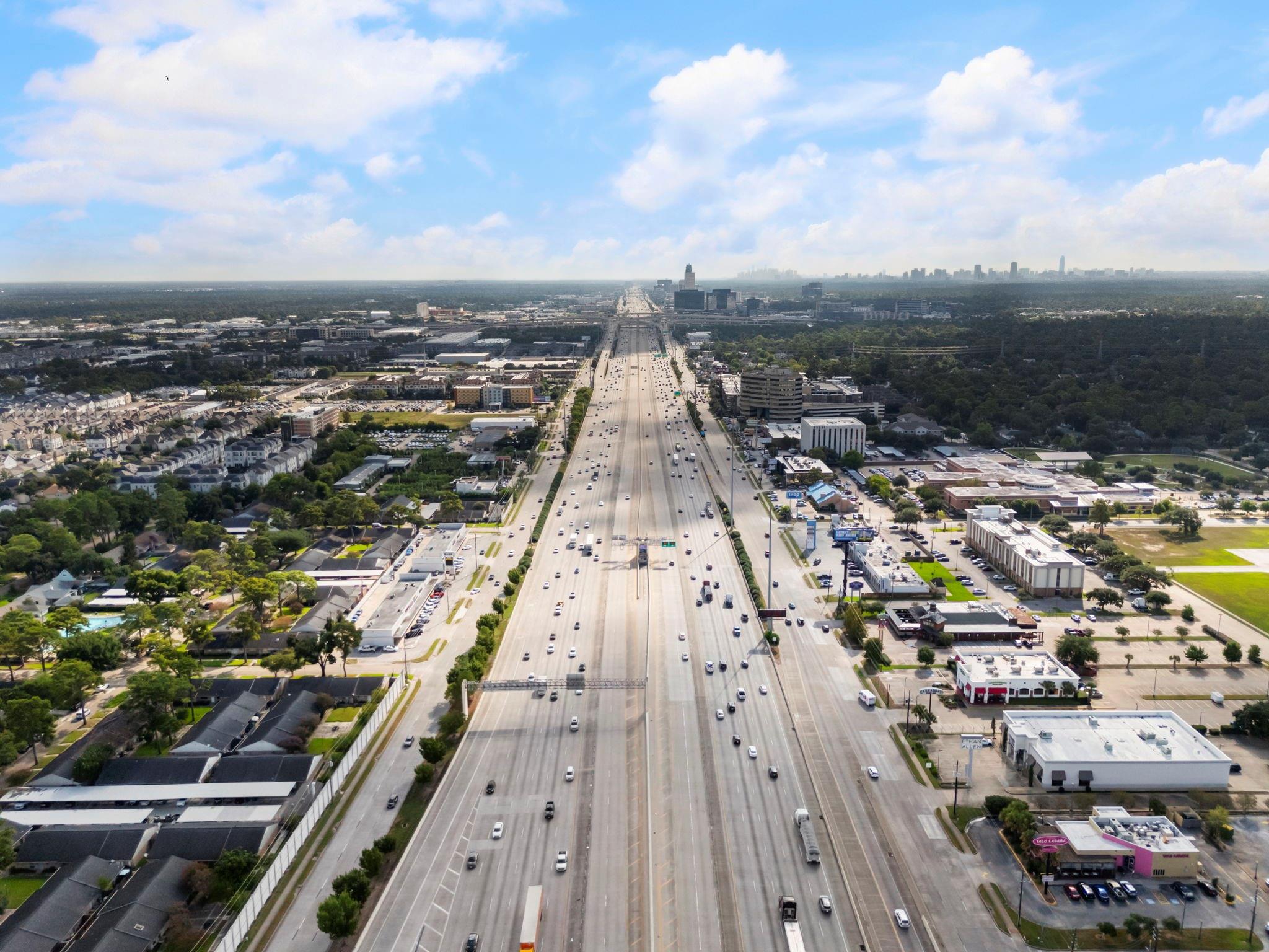 Aerial view of a busy Houston freeway leading toward the downtown skyline.