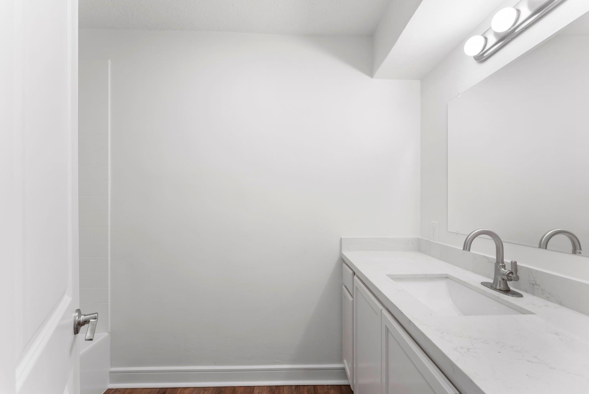 Bathroom vanity with a marble-look counter, large mirror, and brushed-metal faucet.