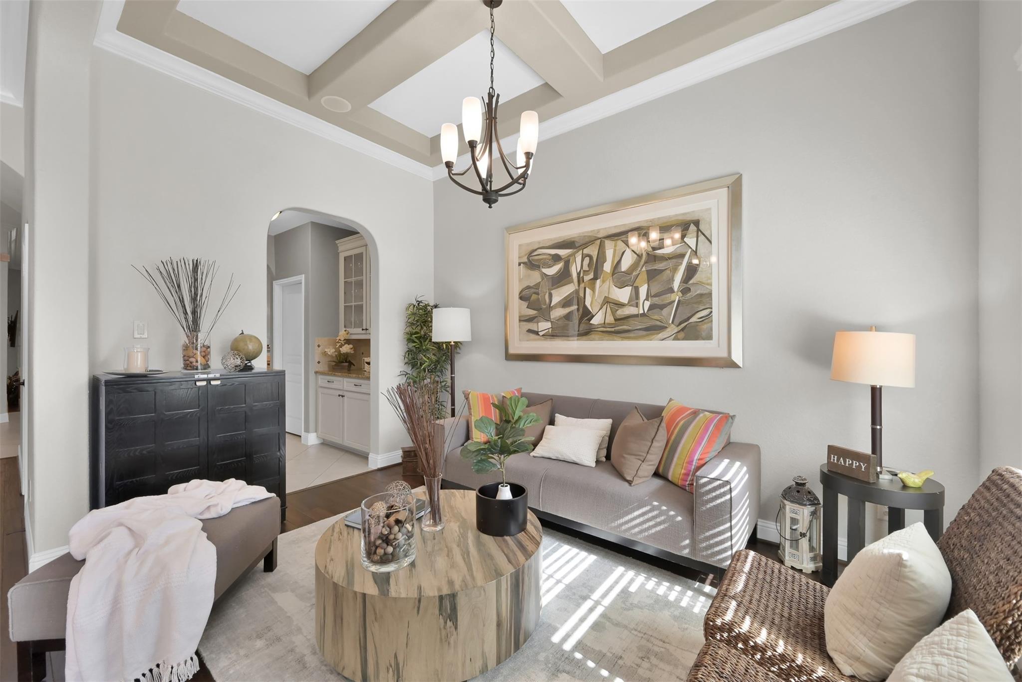Staged living room with gray sofa, colorful striped pillows, round wood coffee table, and tray ceiling.