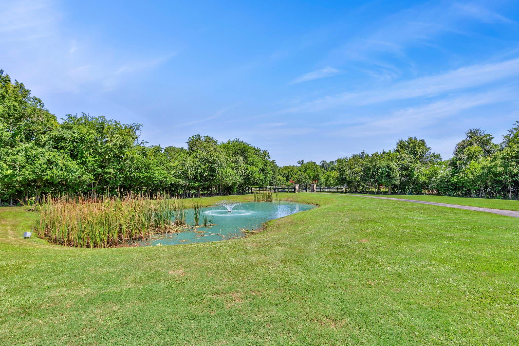 Landscaped grounds with a fountain pond, broad lawn, and mature trees.