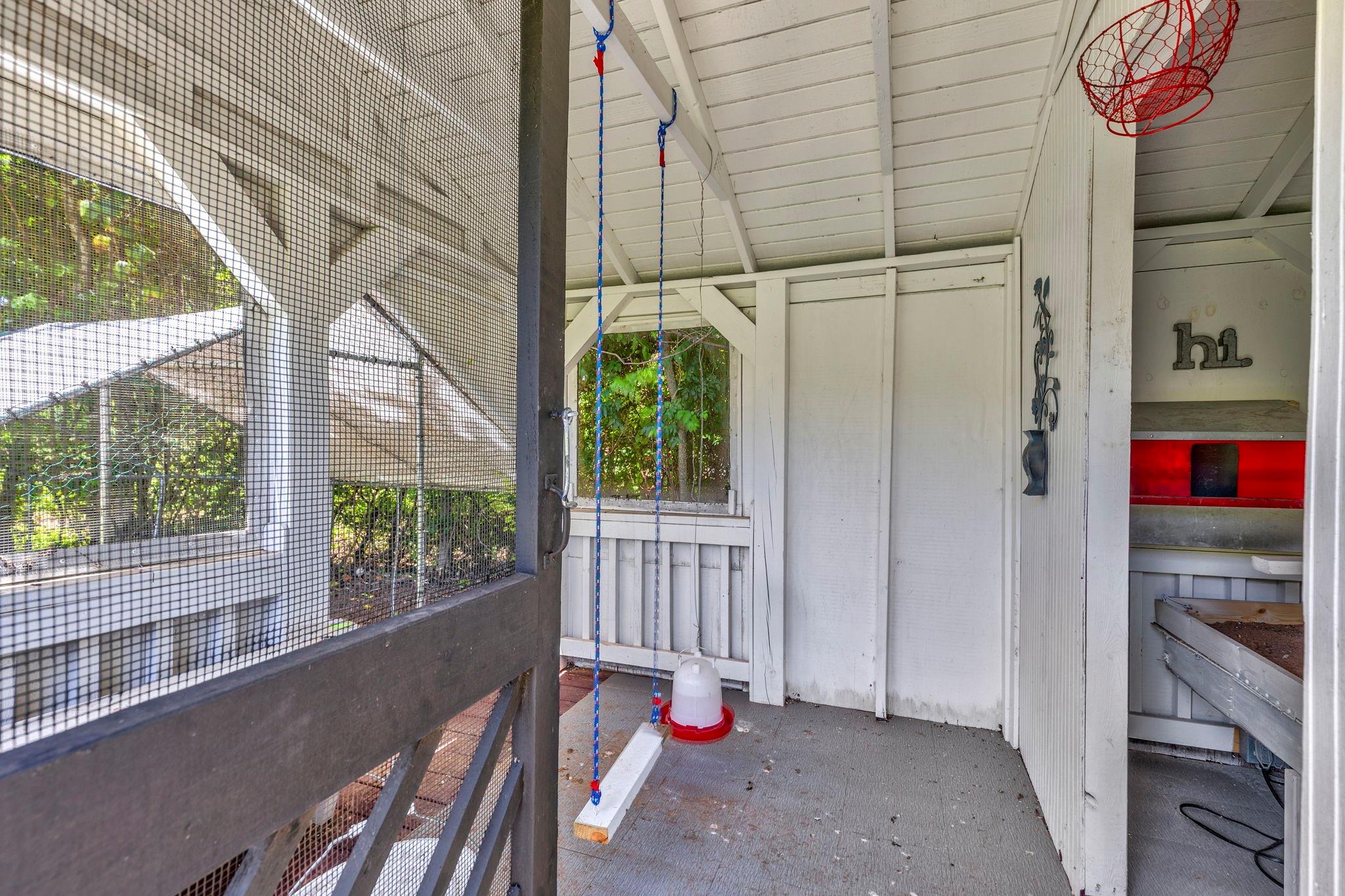 Screened porch with a hanging swing, basketball hoop, and chicken nesting area.