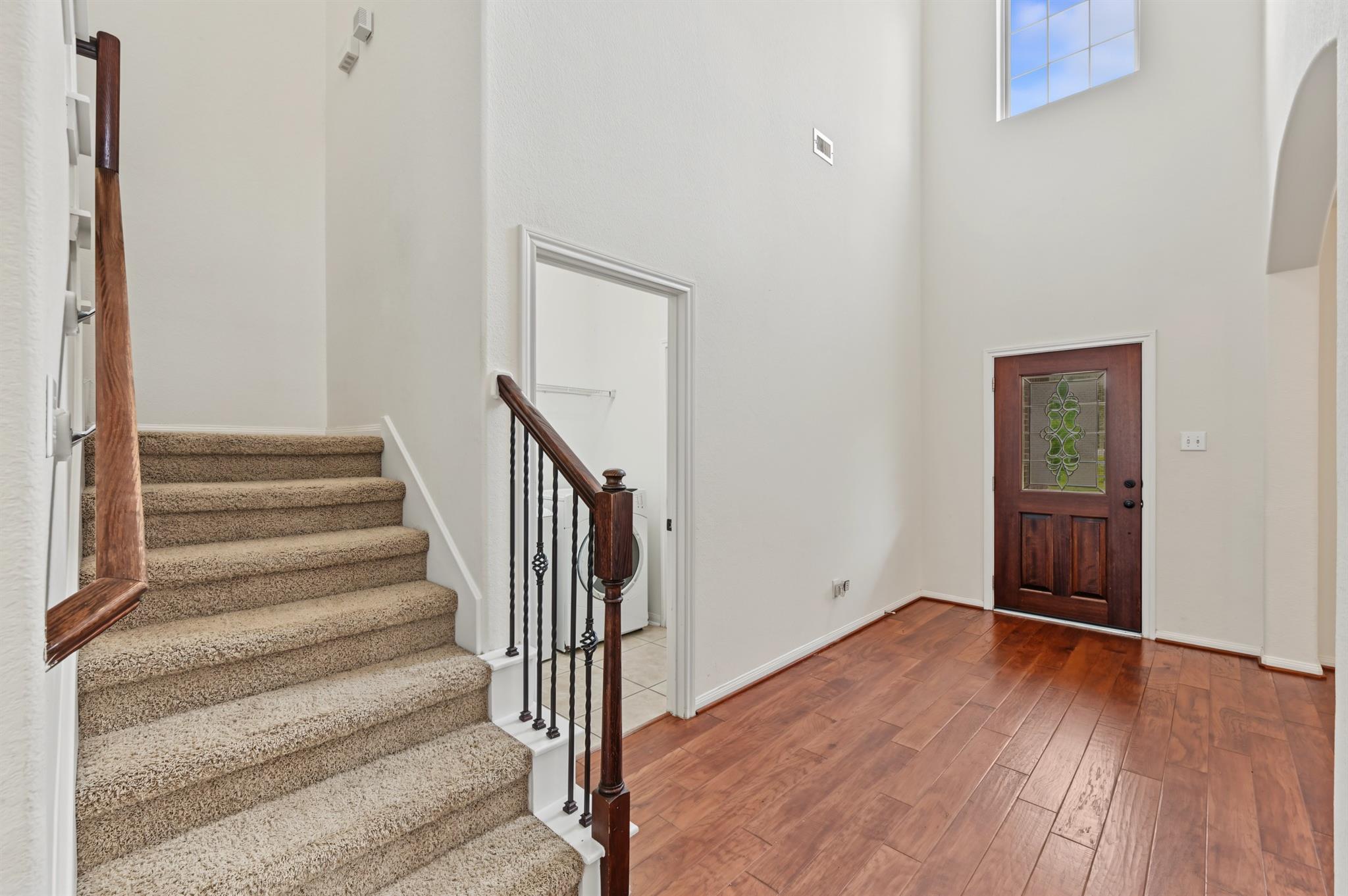 Entry foyer with a carpeted staircase, hardwood floors, and a stained-glass front door.