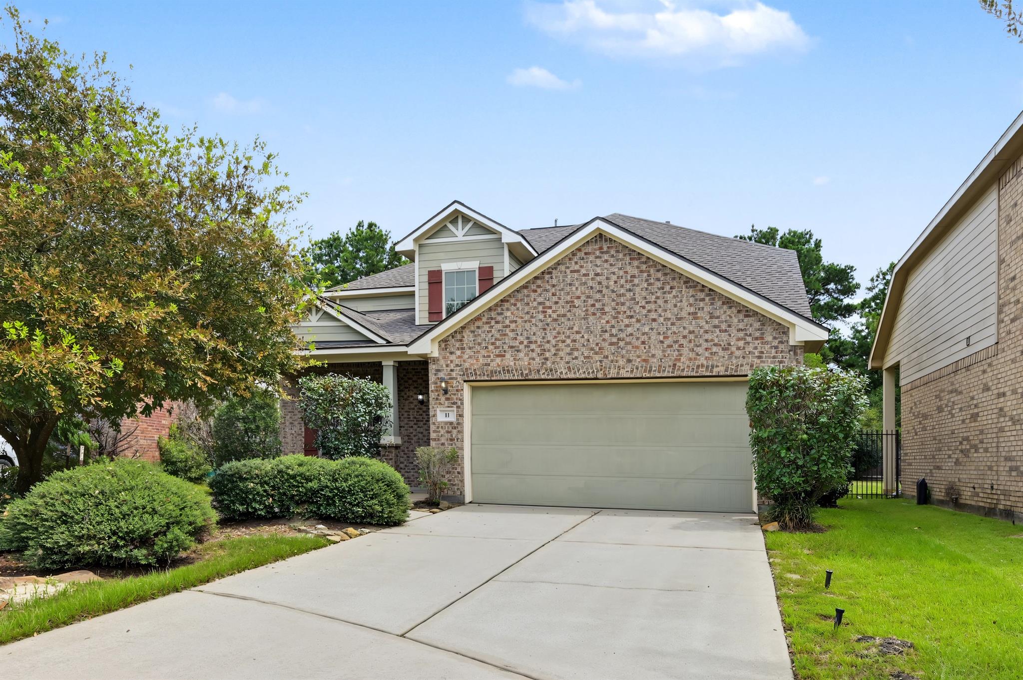 Two-story brick house with a wide garage, concrete driveway, and landscaped front yard.