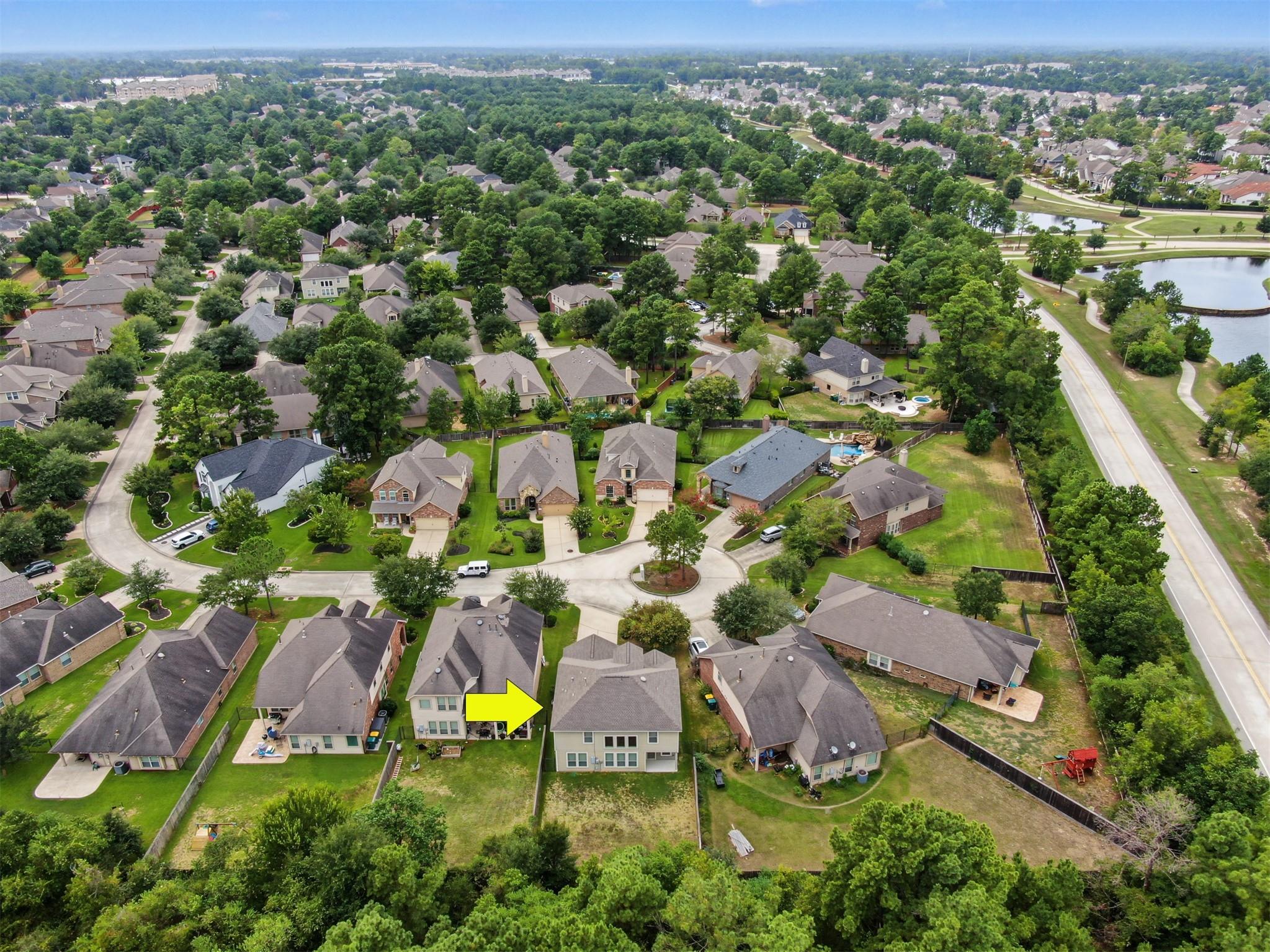 Aerial neighborhood view highlighting a two-story home with a yellow arrow beside a cul-de-sac.