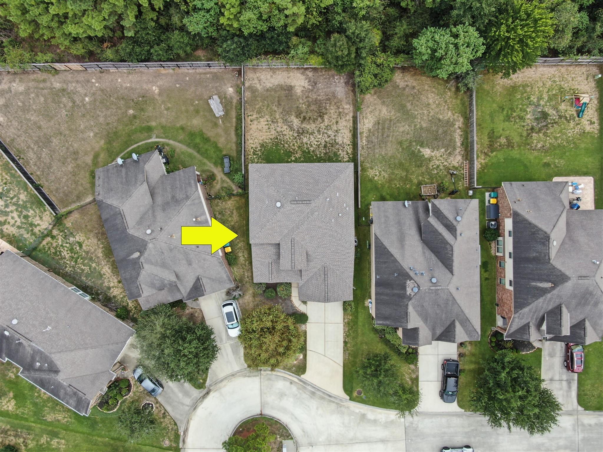 Aerial view of the arrow-marked home among neighboring houses and fenced yards near a cul-de-sac.