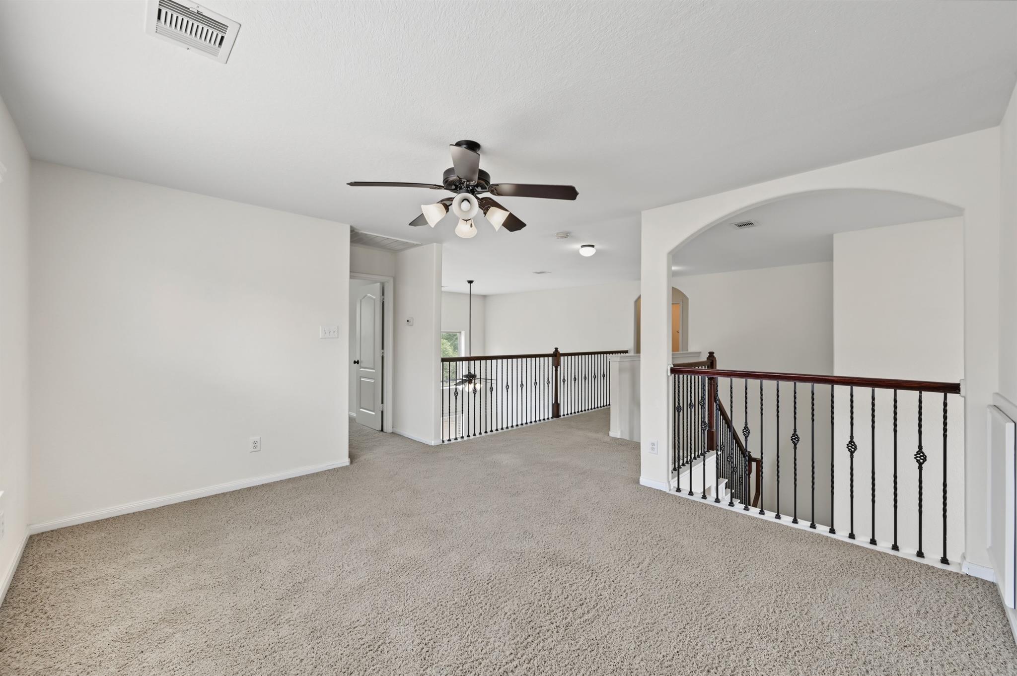 Carpeted upstairs landing with a ceiling fan and dark handrails around the staircase.