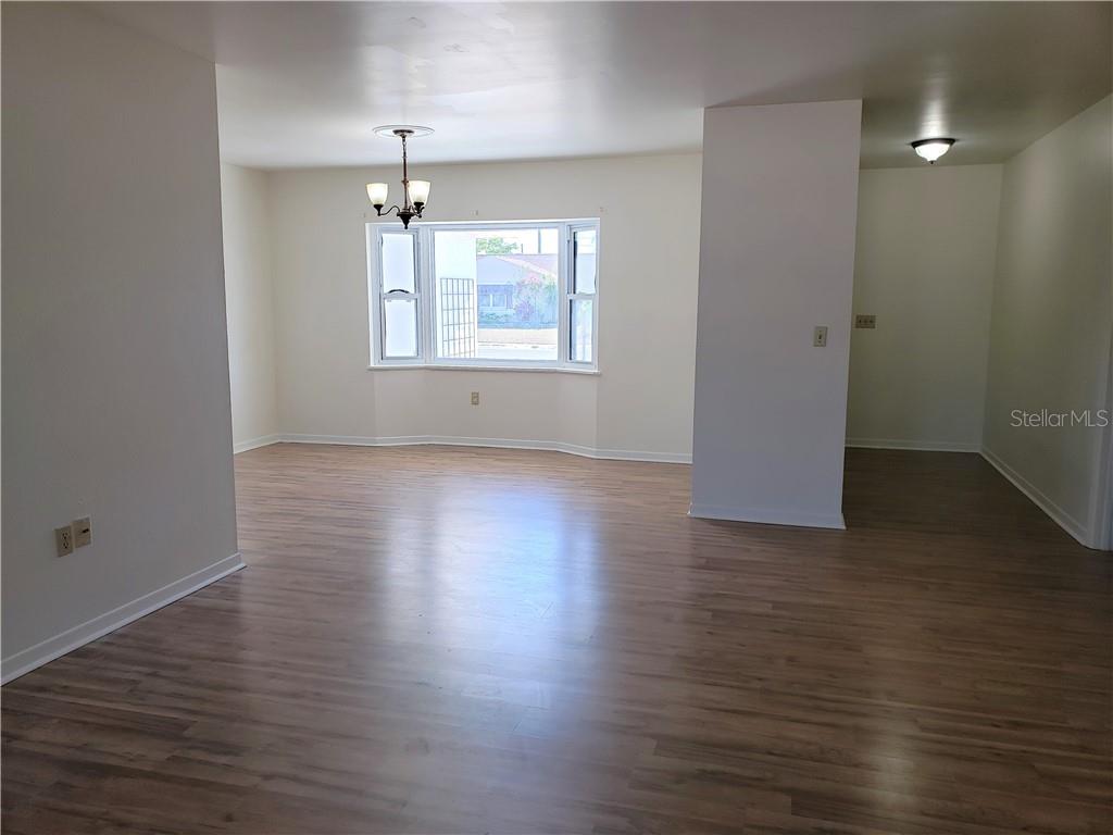 Vacant dining area with wood-look floors, chandelier, and a wide window.