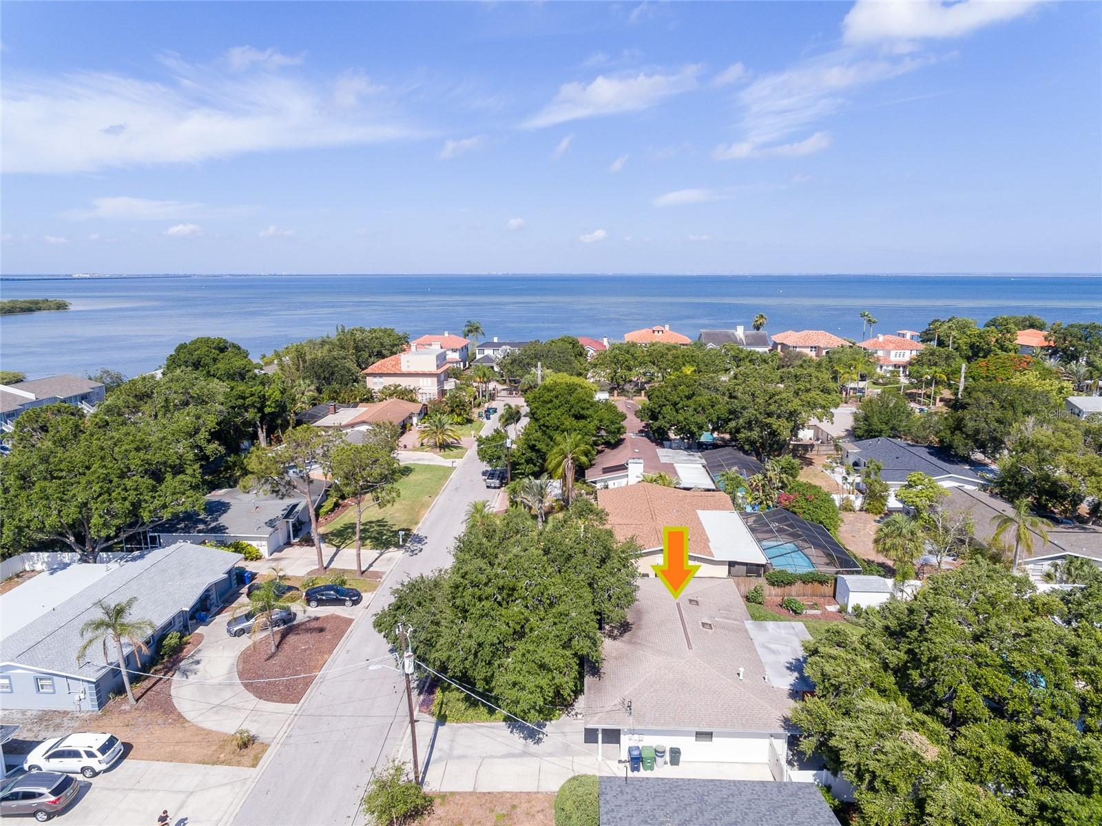 Aerial view of the marked home in a tree-lined neighborhood beside the bay.