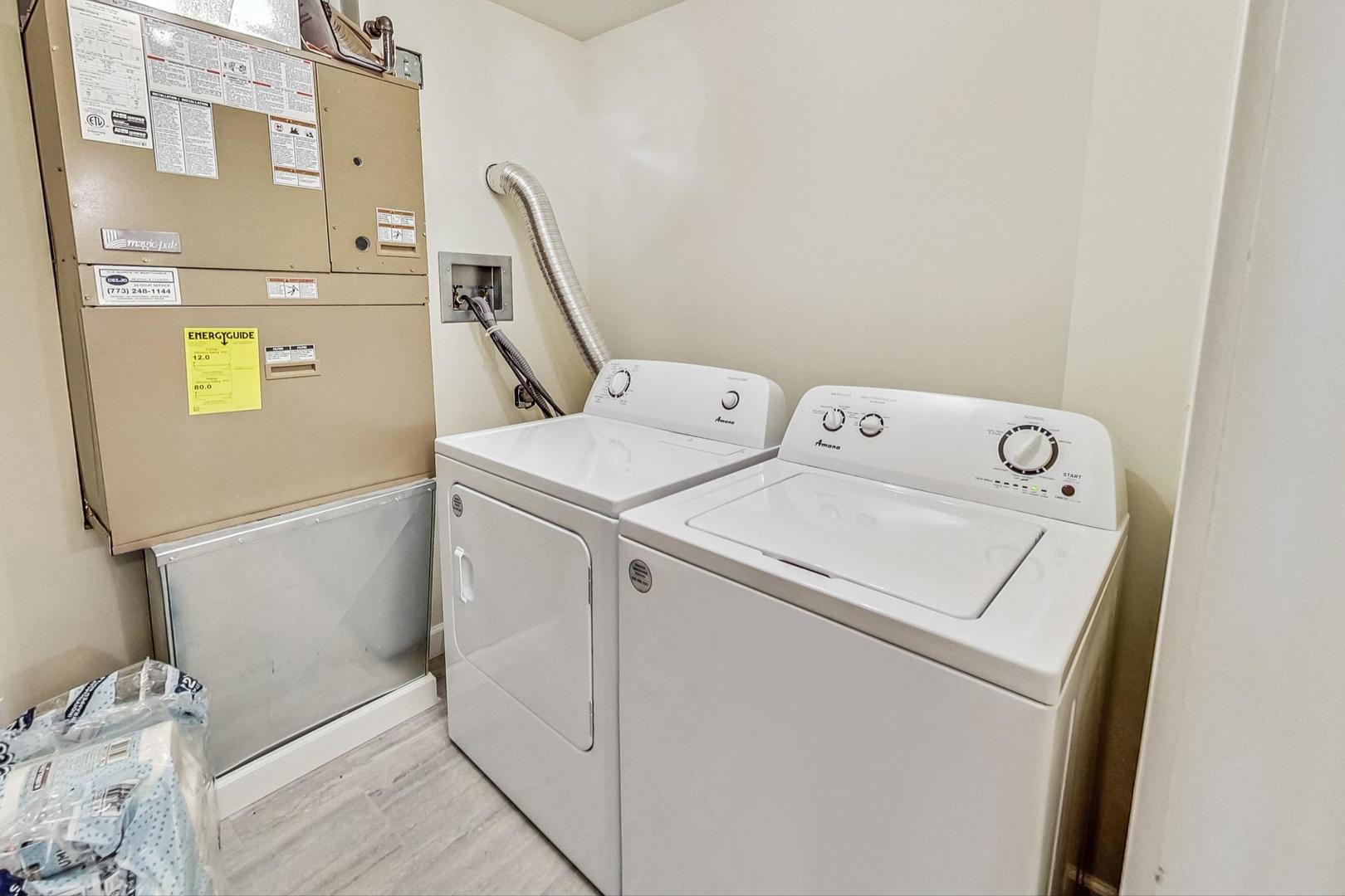 Laundry room with a white washer and dryer beside a large utility furnace.
