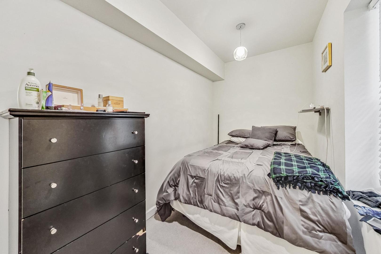 Bedroom with gray bedding, a plaid blanket, and a dark dresser.