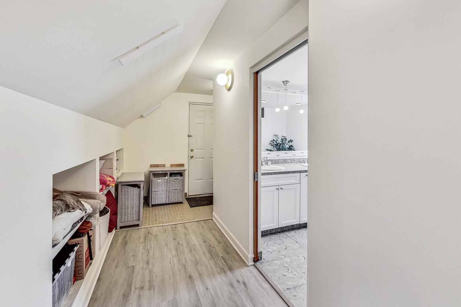 Narrow hallway with built-in storage and an open doorway to a bathroom vanity.