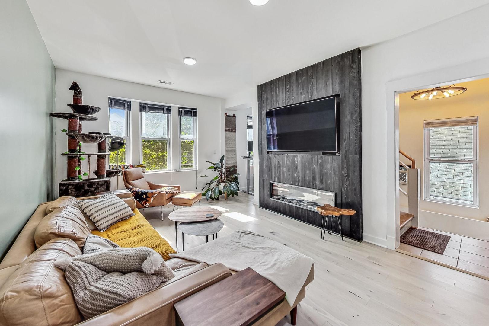 Living room with a leather sectional and a fireplace set into a dark wood accent wall.
