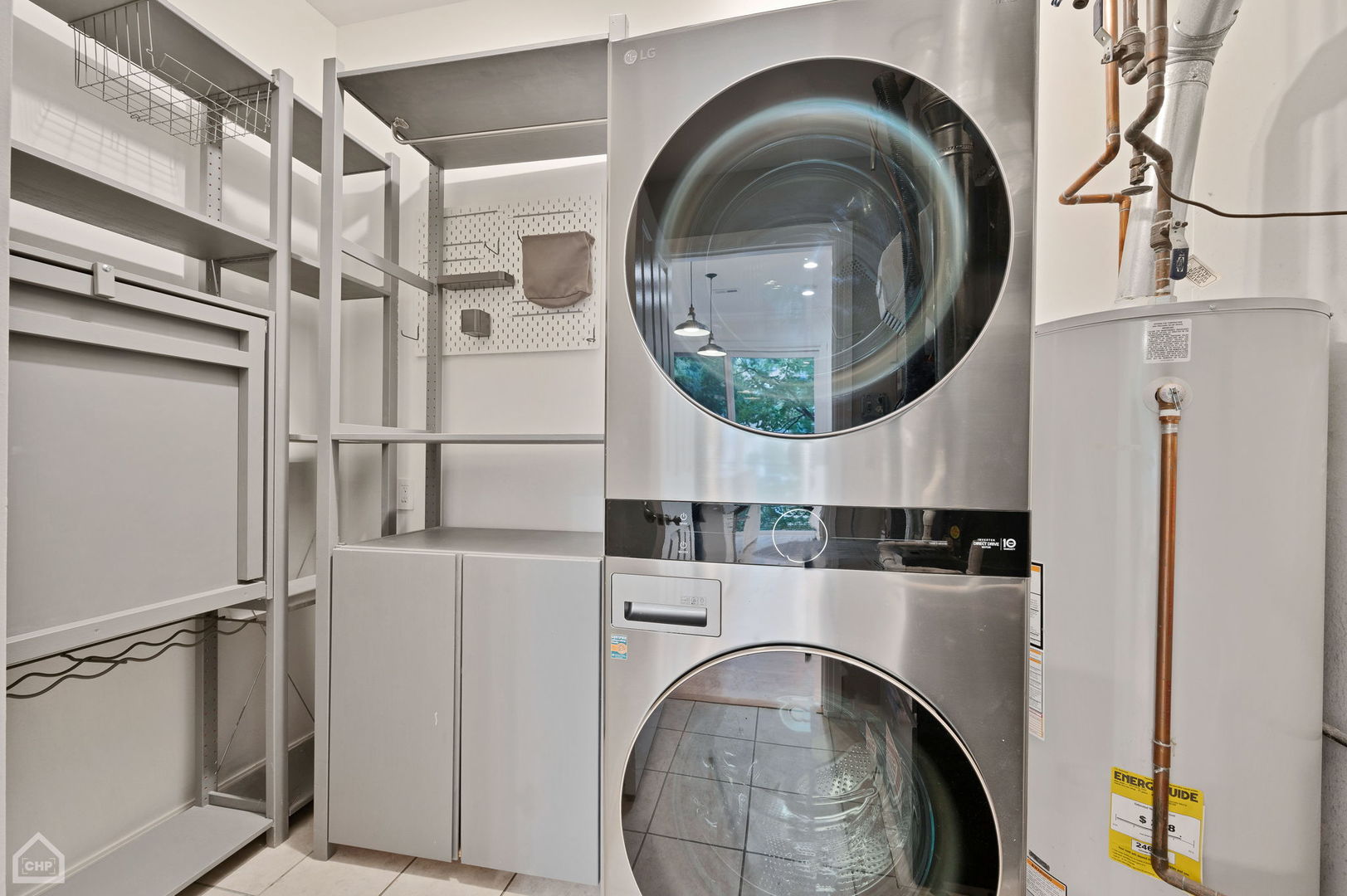 Laundry room with stacked stainless steel washer and dryer, built-in shelving, and a water heater.