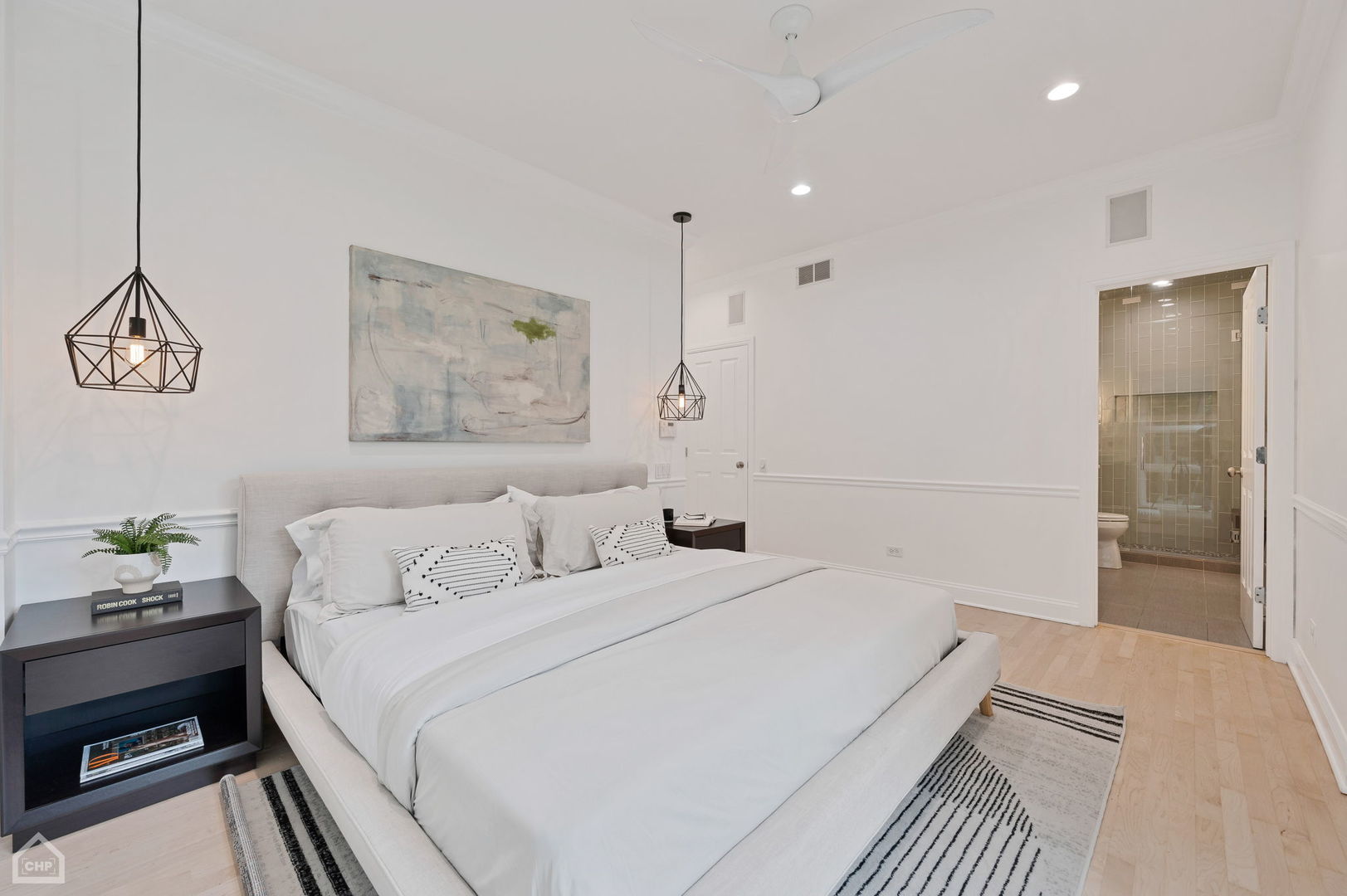 Staged bedroom with a large white bed and an open doorway to a tiled ensuite bathroom.