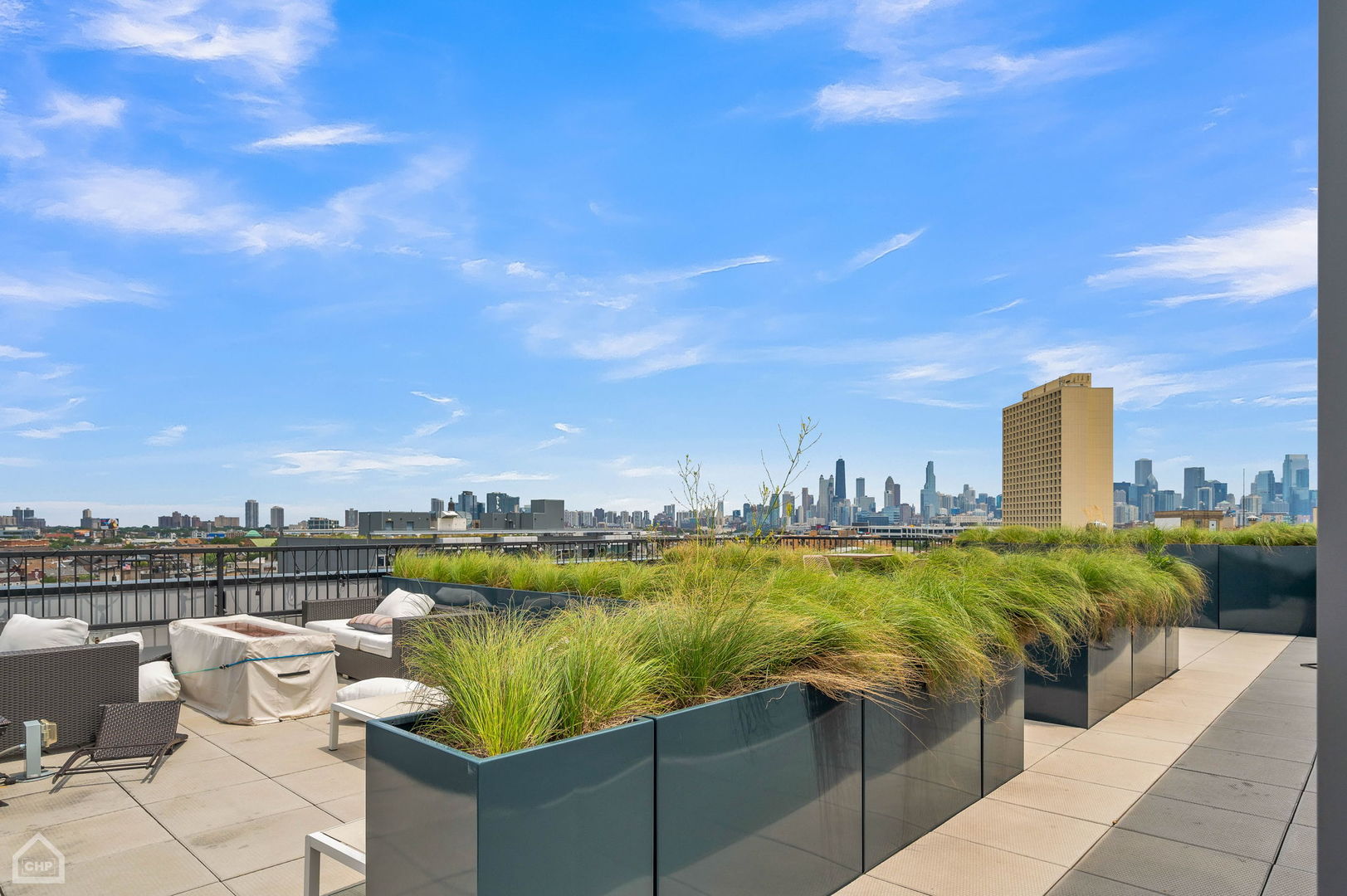 Rooftop terrace with grassy planters, lounge seating, and a wide view of the Chicago skyline.
