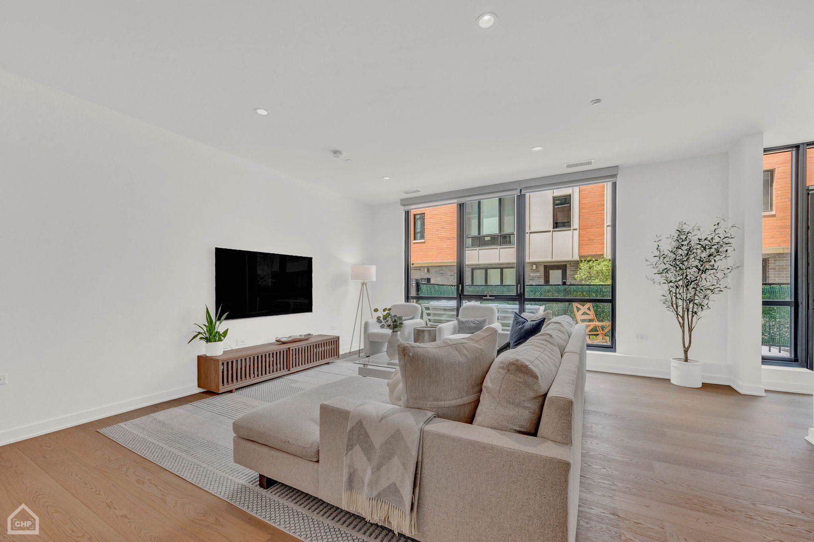 Furnished living room with a large sectional sofa and floor-to-ceiling windows.
