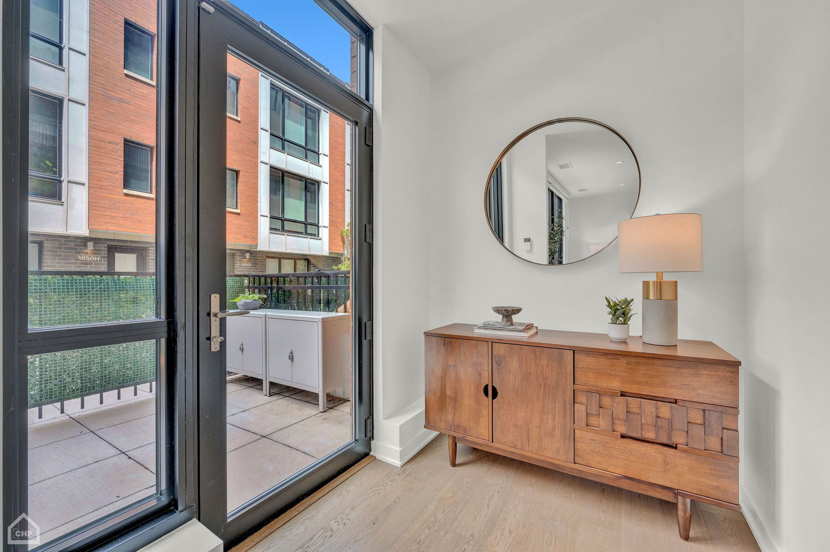 Staged interior with a wooden console beside glass doors opening to a tiled patio.
