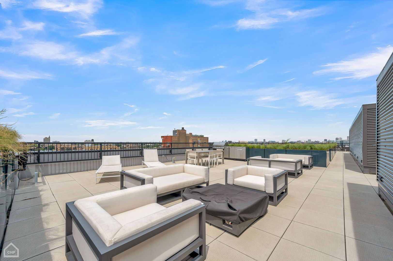 Rooftop terrace with lounge seating, an outdoor kitchen, and Chicago skyline views.
