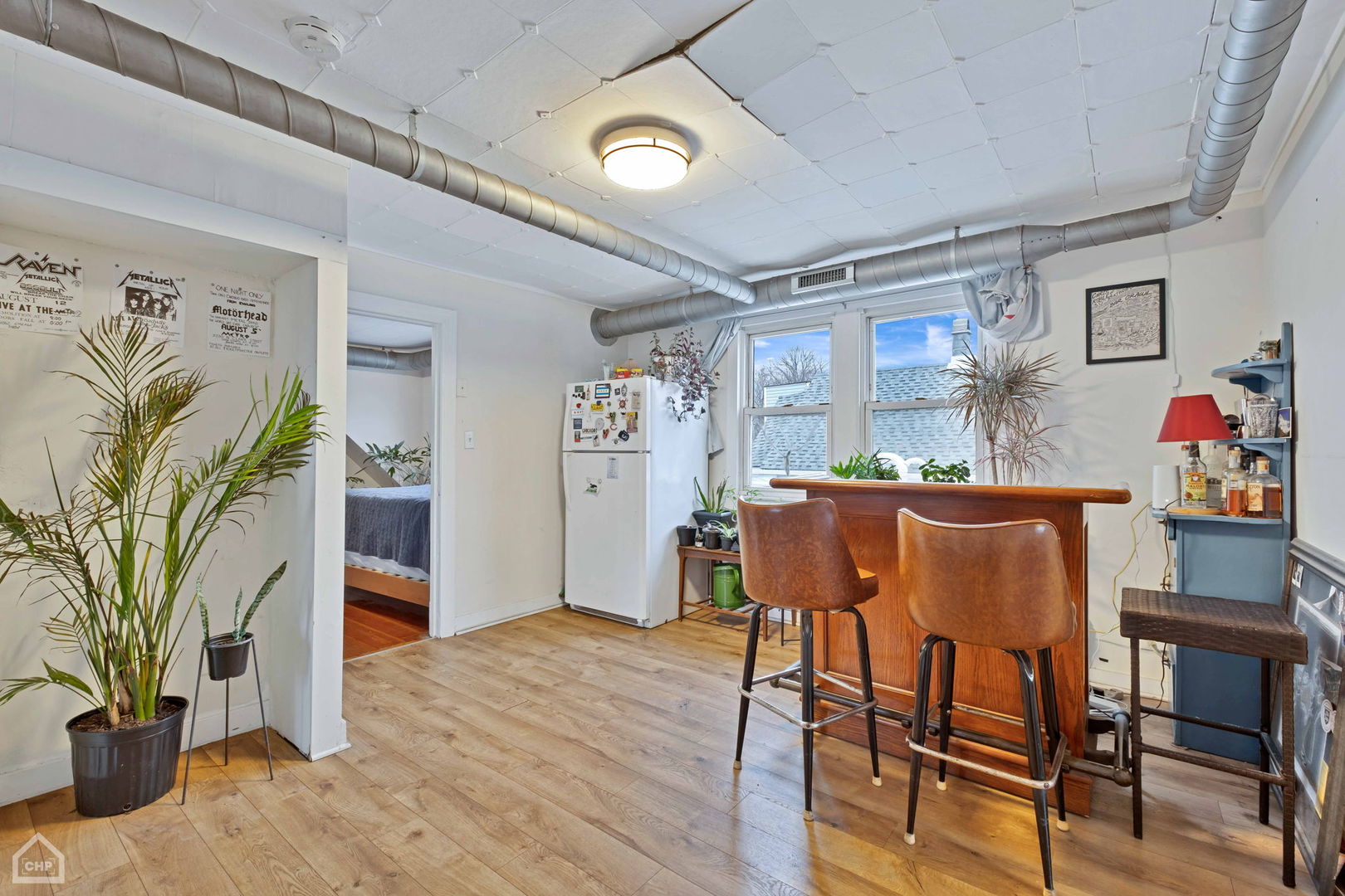 Kitchen and bar area with a wooden counter, leather stools, refrigerator, and exposed ductwork.