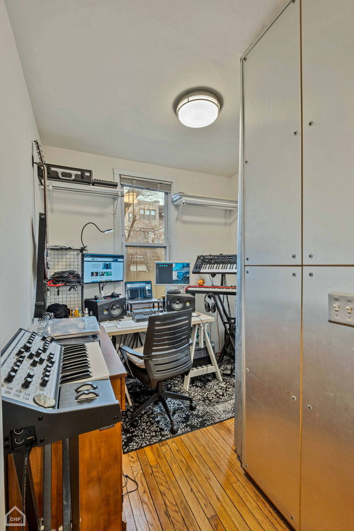 Home music studio with keyboards, recording equipment, and a desk beside a window.