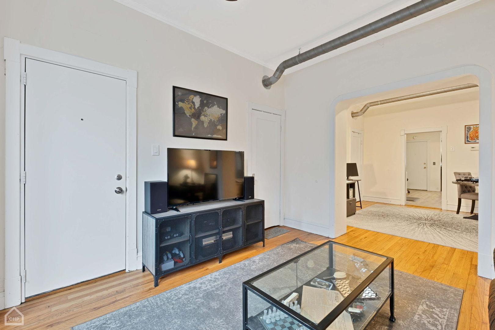 Living room with hardwood floors, a glass coffee table, and an arched opening to an adjoining sitting area.