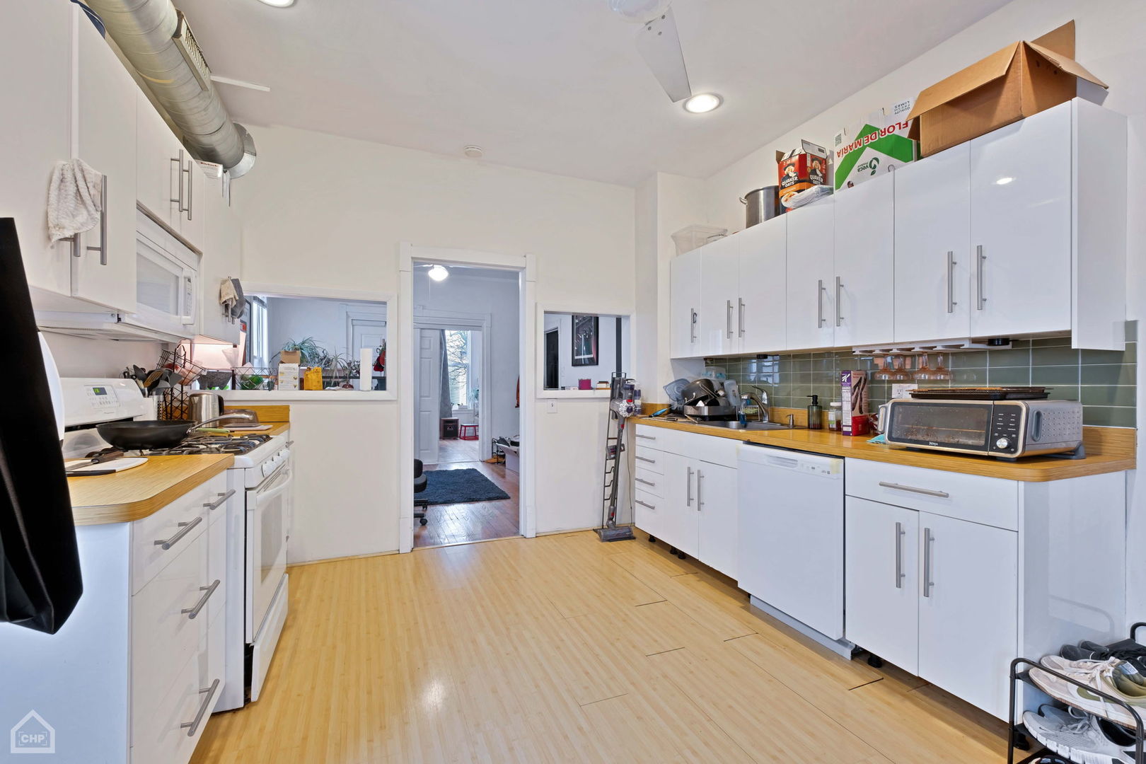 Kitchen with white cabinets, wood countertops, green tile backsplash, and an exposed metal ceiling duct.