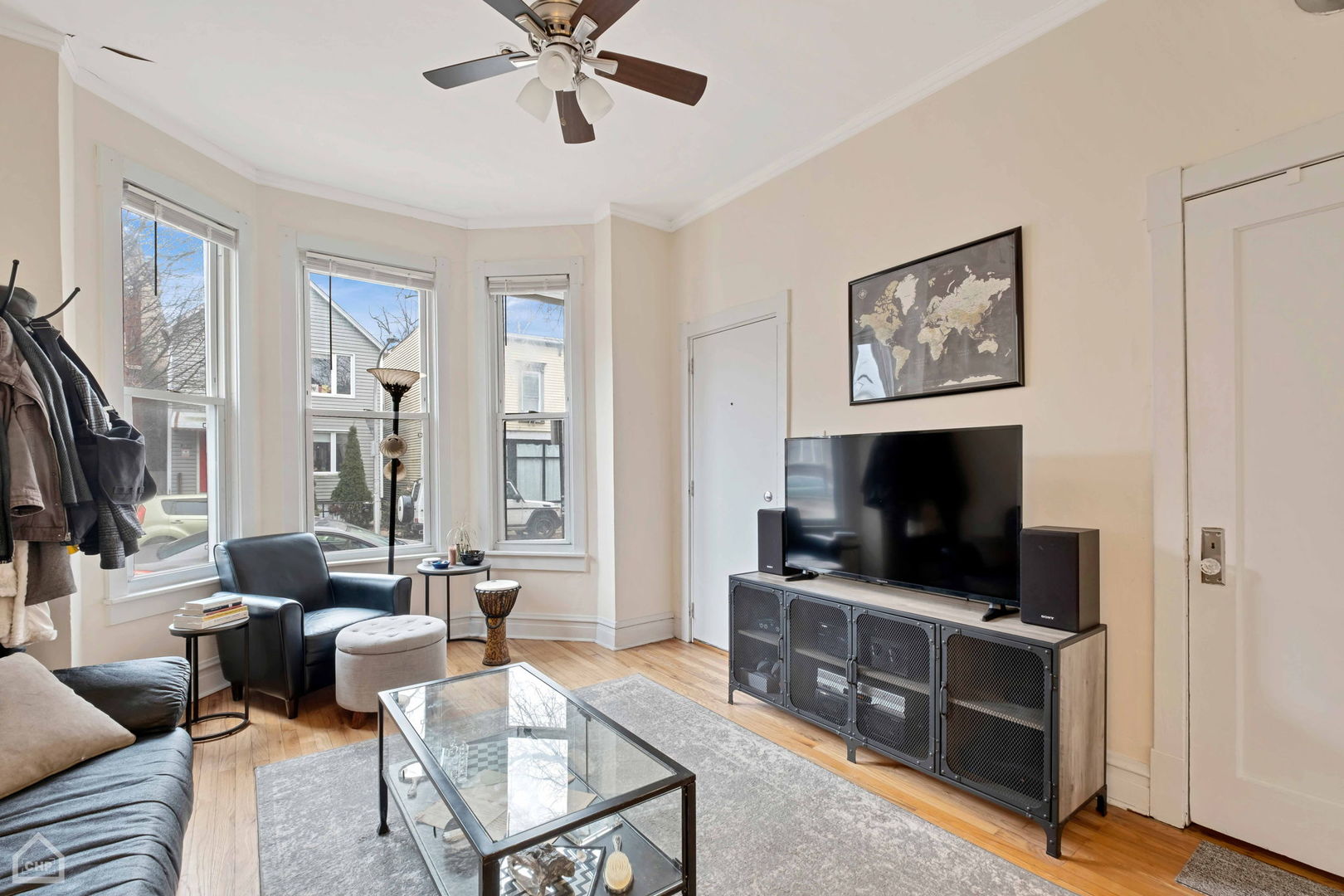 Living room with bay windows, hardwood floors, and a TV above a metal-front media console.